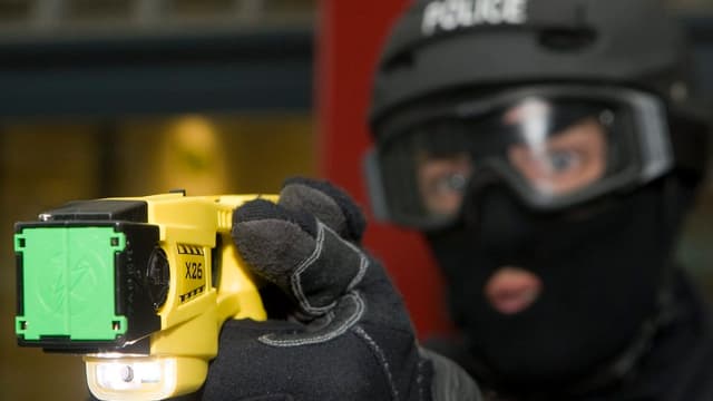 Polizist zielt mit Taser. Polizist zielt mit Taser.