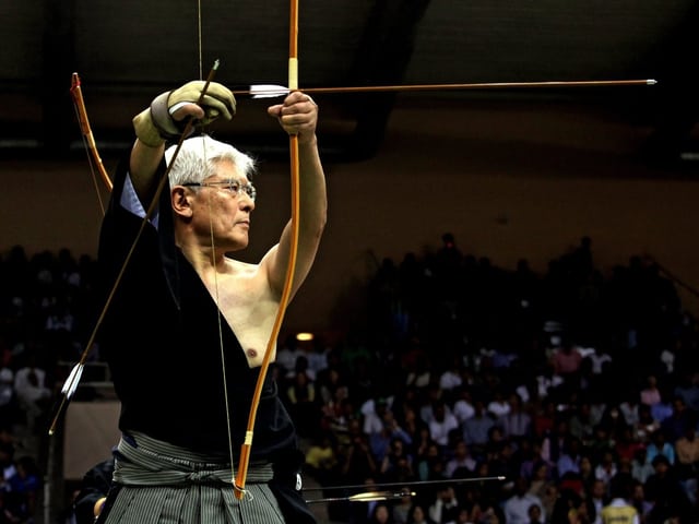 Japanischer Kyudo-Bogenschütze in Aktion. Japanischer Kyudo-Bogenschütze in Aktion.