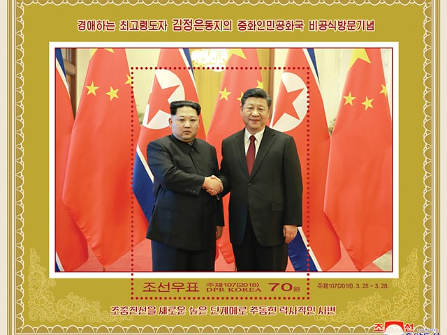 Briefmarke mit Bild, auf dem sich Kim und Xi die Hand geben. Briefmarke mit Bild, auf dem sich Kim und Xi die Hand geben.