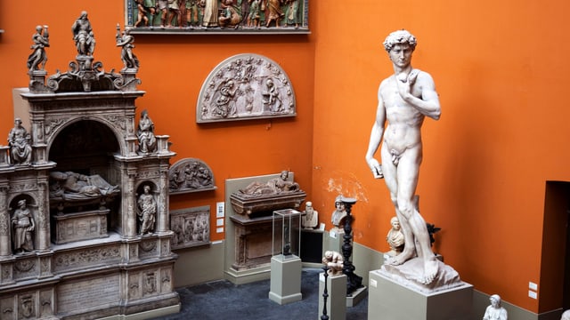 Michelangelos David und andere Stein-Figuren vor der orangefarbenen Wand des V&A Museum Michelangelos David und andere Stein-Figuren vor der orangefarbenen Wand des V&A Museum