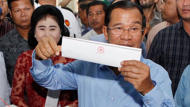 Hun Sen hält seinen Wahlzettel in die Kameras. Hun Sen hält seinen Wahlzettel in die Kameras.