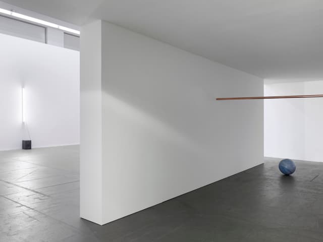 Ein fast leerer Museumsraum: auf dem Boden eine blaue Steinkugel und darüber eine goldene Stange. Ein fast leerer Museumsraum: auf dem Boden eine blaue Steinkugel und darüber eine goldene Stange.