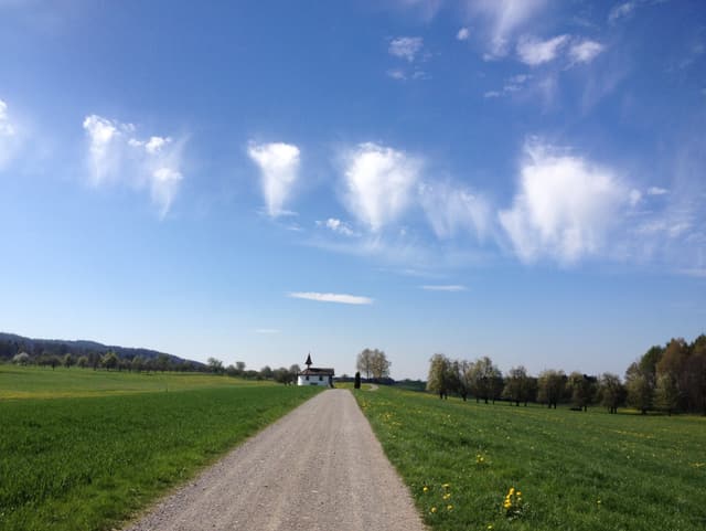 Wolken wie Quallen am blauen Himmel: oben wie ein Wattebausch, unten dünne Streifen.