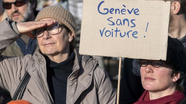 Demonstrantinnen mit einem Schild, das Genf ohne Autos fordert. Demonstrantinnen mit einem Schild, das Genf ohne Autos fordert.