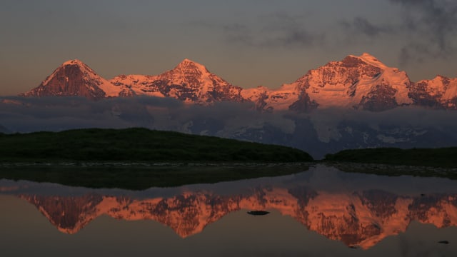 Friedliche Abendstimmung mit Alpenglühen an Eiger, Mönch und Jungfrau an einem kleinen Bergsee im Lauterbrunnental.
