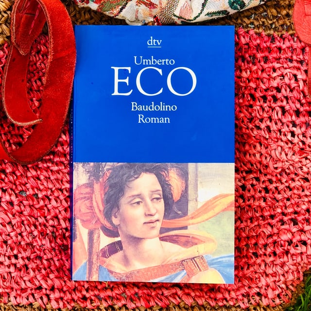 Der Schelmenroman «Baudolino» von Umberto Eco liegt auf einer Beuteltasche Der Schelmenroman «Baudolino» von Umberto Eco liegt auf einer Beuteltasche