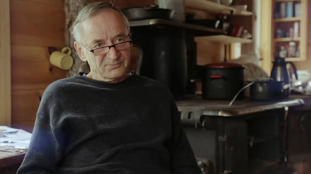 Ein Mann mit Brille und kurzen, grauen Haaren sitzt in seinem Häuschen. Ein Mann mit Brille und kurzen, grauen Haaren sitzt in seinem Häuschen.