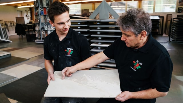 junger Mann und älterer Mann schauen eine Bodenplatte an. junger Mann und älterer Mann schauen eine Bodenplatte an.