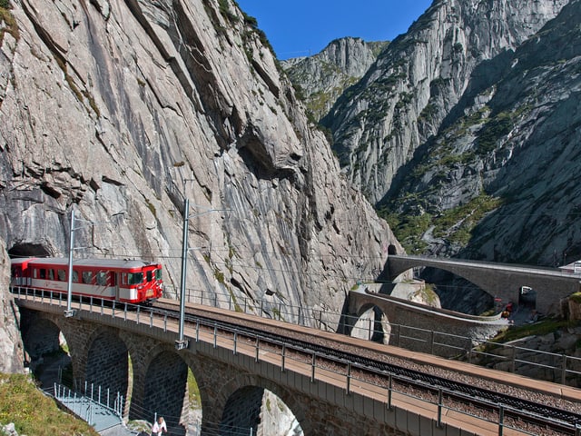 Die Bahn auf dem Weg durch die Schöllenenschlucht entlang der alten Teufelsbrücke im Kanton Uri. Die Bahn auf dem Weg durch die Schöllenenschlucht entlang der alten Teufelsbrücke im Kanton Uri.