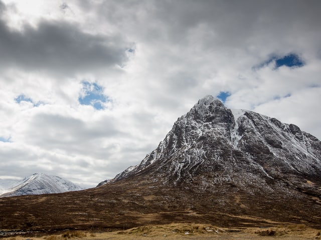 Verschneiter, felsiger Berg mit noch aperem, grasigen Vorland. Verschneiter, felsiger Berg mit noch aperem, grasigen Vorland.