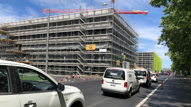 Blick auf zwei Gebäude im Rohbau. Im Vordergrund stehen Auto in einem Verkehrsstau. Blick auf zwei Gebäude im Rohbau. Im Vordergrund stehen Auto in einem Verkehrsstau.