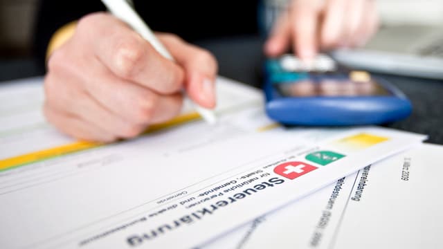 Eine Person füllt eine Steuererklärung aus Eine Person füllt eine Steuererklärung aus