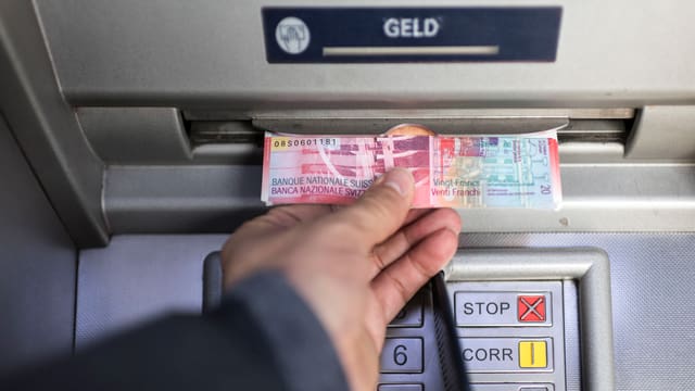 Jemand nimmt Geld aus einem Bankomaten. Jemand nimmt Geld aus einem Bankomaten.