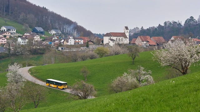 Aufnahme Dorf, Postauto fährt auf schmaler Strasse zu den Häusern Aufnahme Dorf, Postauto fährt auf schmaler Strasse zu den Häusern