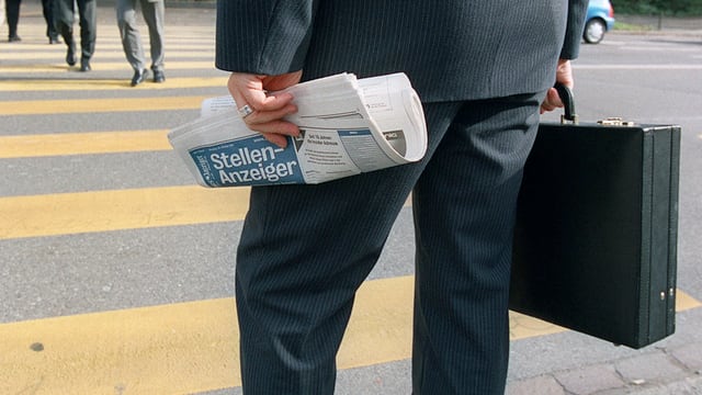 Ein Geschäftsmann hält einen Aktenkoffer und den Stellenanzeiger in der Hand. Ein Geschäftsmann hält einen Aktenkoffer und den Stellenanzeiger in der Hand.