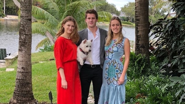 Zwei junge Frauen, ein junger Mann in der Mitte mit Hund auf dem Arm. Zwei junge Frauen, ein junger Mann in der Mitte mit Hund auf dem Arm.