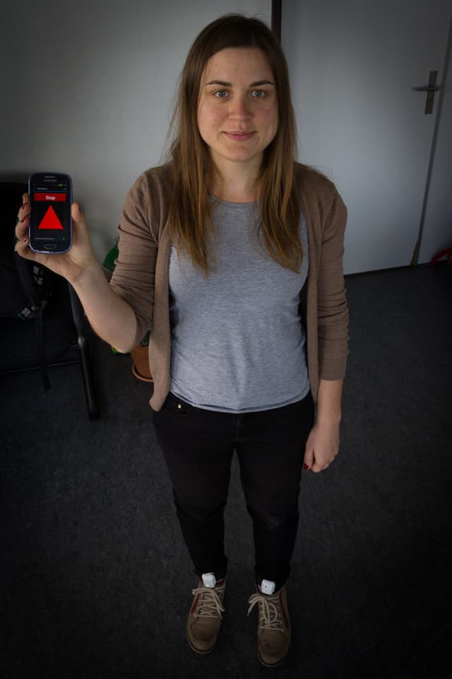 Eine junge Frau hält ein Smartphone in der Hand, an den Füssen sind Sensoren befestigt. Eine junge Frau hält ein Smartphone in der Hand, an den Füssen sind Sensoren befestigt.