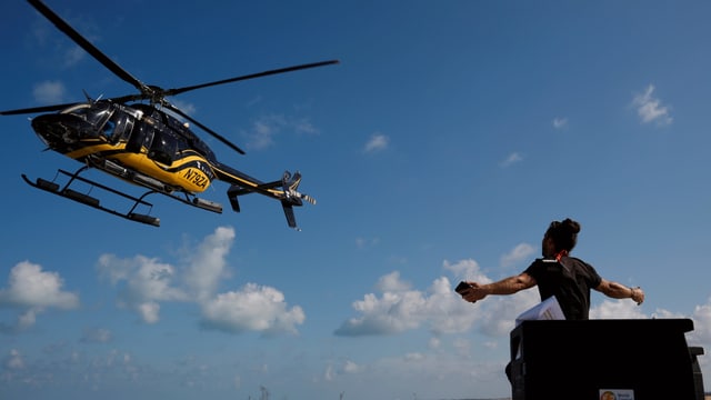 Ein Mann gestikuliert in Richtung eines Helikopters Ein Mann gestikuliert in Richtung eines Helikopters