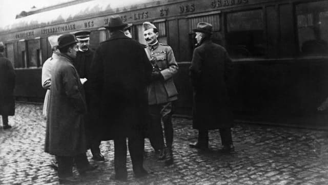 Männer in Uniform und Zivilkleidern vor einem Zug stehend. Männer in Uniform und Zivilkleidern vor einem Zug stehend.
