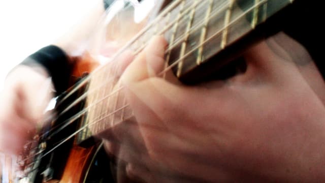 Verschwommenes Bild: Zwei Hände auf einem Bass. Verschwommenes Bild: Zwei Hände auf einem Bass.