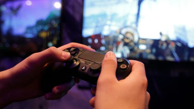 Zwei Hände halten einen Playstation-4-Controller. Zwei Hände halten einen Playstation-4-Controller.