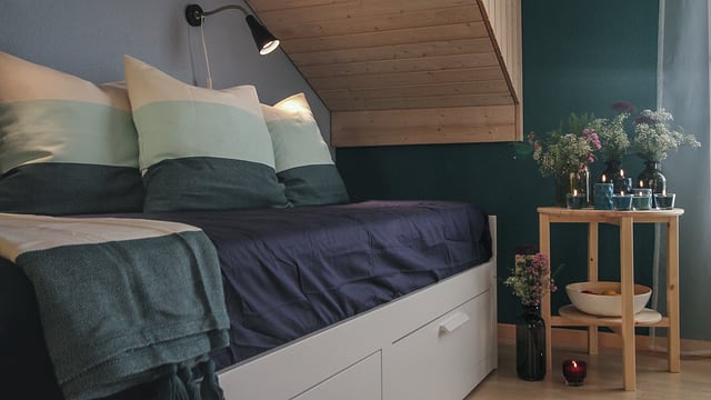 In der Erholungsecke stehen ein Bettsofa und einen hölzernen Beistelltisch. Die türkis-blauen Farben bringen Ruhe in den Raum. In der Erholungsecke stehen ein Bettsofa und einen hölzernen Beistelltisch. Die türkis-blauen Farben bringen Ruhe in den Raum.