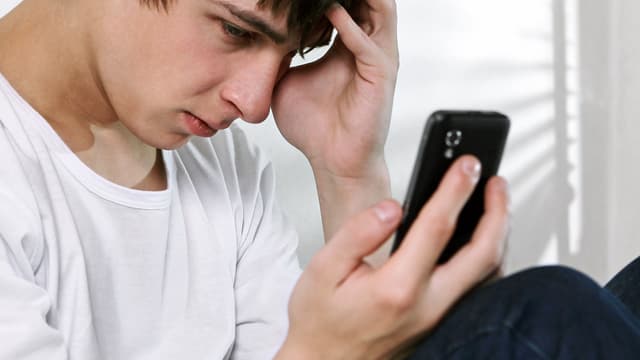 Junge schaut auf Handy Junge schaut auf Handy
