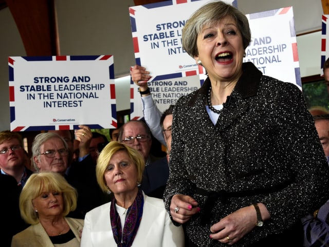 May erhöht und von Anhängern umringt, die Transparente mit ihrem Wahlkampfmotto hoch halten. May erhöht und von Anhängern umringt, die Transparente mit ihrem Wahlkampfmotto hoch halten.