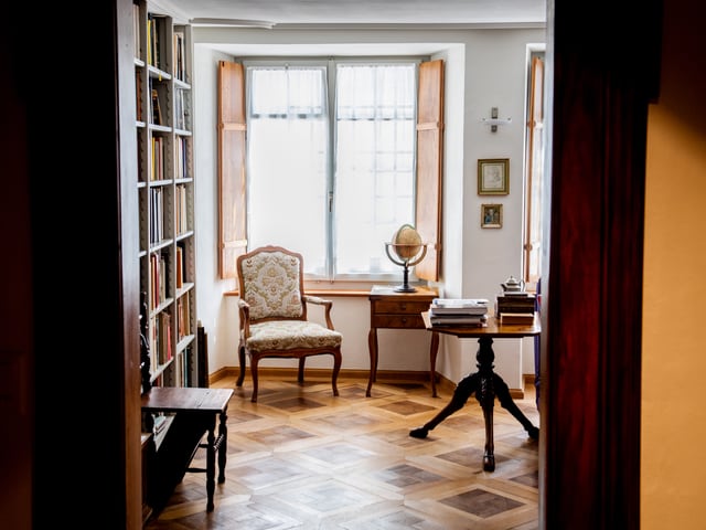 Ein Blick in ein Wohnzimmer mit Parkettboden, Bücherregal, Sessel. Ein Blick in ein Wohnzimmer mit Parkettboden, Bücherregal, Sessel.