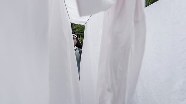 Eine Nonne hinter aufgehängten Tüchern. Eine Nonne hinter aufgehängten Tüchern.