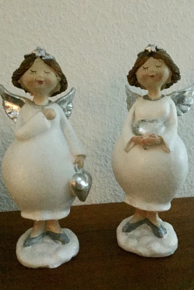 ZWei Engel aus Porzellan mit silbernen Flügeln.
