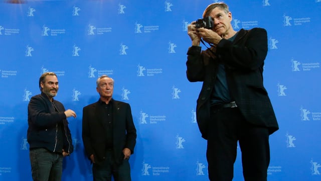 Joaquin Phoenix und Udo Kier im Hintergrund, Gus Van Sant vorne im Blitzlichtgewitter der Berlinale. Joaquin Phoenix und Udo Kier im Hintergrund, Gus Van Sant vorne im Blitzlichtgewitter der Berlinale.