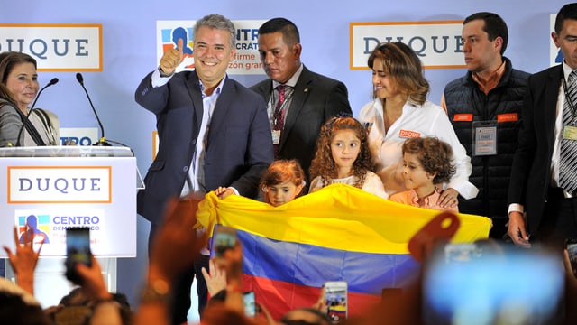 Ivan Duque feiert mit seinen Kinder, die eine Flagge Kolumbiens halten Ivan Duque feiert mit seinen Kinder, die eine Flagge Kolumbiens halten