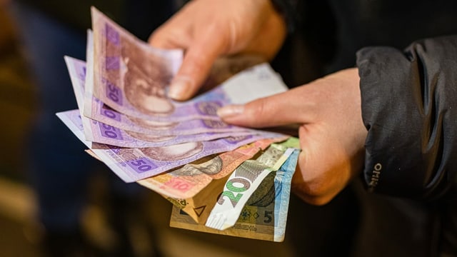 Ein flychtlingsfrau hlt ukrainisches Geld in den Handen