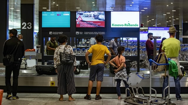 Passagiere warten beim Gepäckband am Flughafen