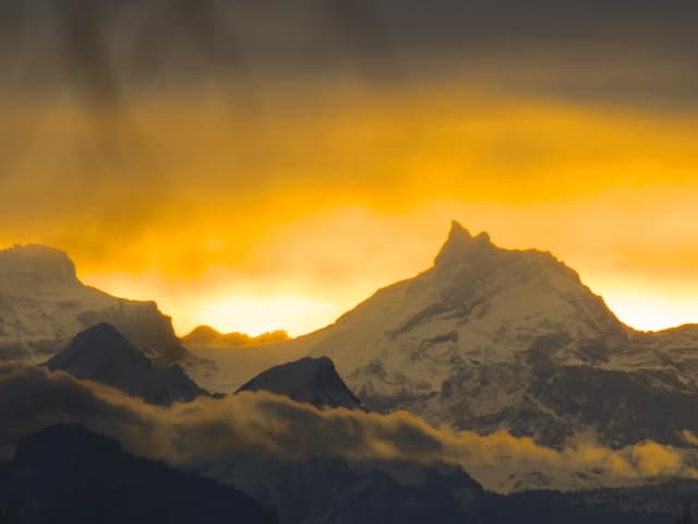 Das Scherenhorn in Luzern ist in oranges Licht gehüllt, der teils bewölkte Himmel darüber schimmert gelborange.