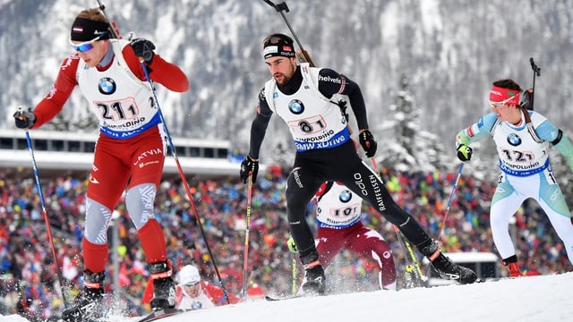 Drei Biathleten laufen sich auf Skiern nach. Das Gewehr haben sie auf dem Rücken angeschnallt. Drei Biathleten laufen sich auf Skiern nach. Das Gewehr haben sie auf dem Rücken angeschnallt.
