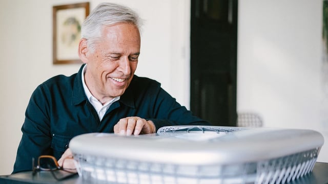 Ein Mann mit grauen Haaren betrachtet ein Modell eines Fussballstadions. Ein Mann mit grauen Haaren betrachtet ein Modell eines Fussballstadions.