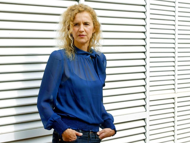 Eine blonde Frau mit blauer Bluse steht vor weissen geschlossenen Rolläden. Eine blonde Frau mit blauer Bluse steht vor weissen geschlossenen Rolläden.