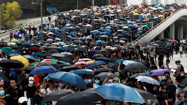 Demonstranten mit Regenschirmen marschieren durch die Strassen Hongkongs. Demonstranten mit Regenschirmen marschieren durch die Strassen Hongkongs.