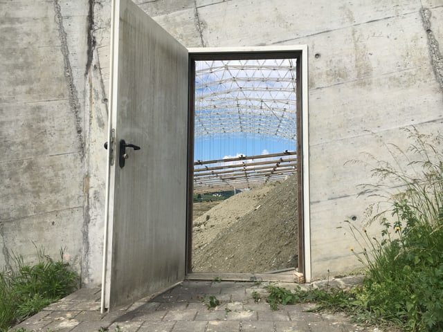 Blick durch eine offene Türe in die leere Sondermülldeponie-Halle Blick durch eine offene Türe in die leere Sondermülldeponie-Halle