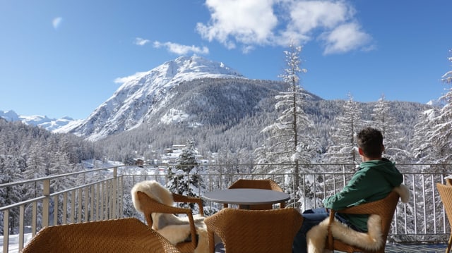 Mann an Tisch auf Terrasse, Blick auf Berg Mann an Tisch auf Terrasse, Blick auf Berg