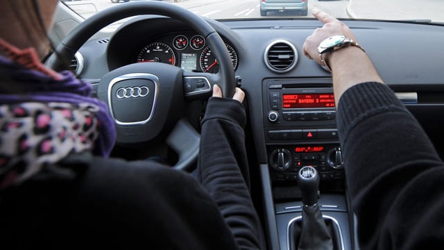 Ein Fahrlehrer zeigt einer Schülerin den Weg. Ein Fahrlehrer zeigt einer Schülerin den Weg.