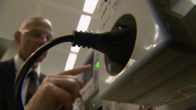 Stecker in einer Steckdose. Im Hintergrund ist ein Mann zu sehen. Stecker in einer Steckdose. Im Hintergrund ist ein Mann zu sehen.