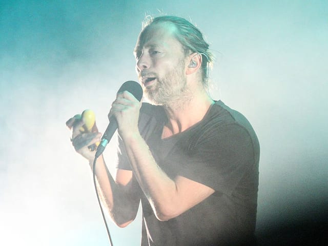 Der Sänger Thom Yorke mit Mikrofon auf einer Bühne. Der Sänger Thom Yorke mit Mikrofon auf einer Bühne.