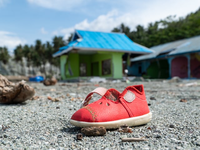 Roter Kinderschuh am Boden Roter Kinderschuh am Boden