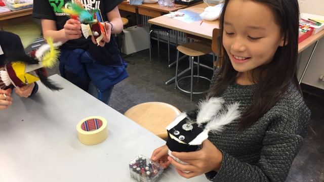 Ein Mädchen hält einen kleinen Roboter mit zwei Federn dran in der Hand. Ein Mädchen hält einen kleinen Roboter mit zwei Federn dran in der Hand.