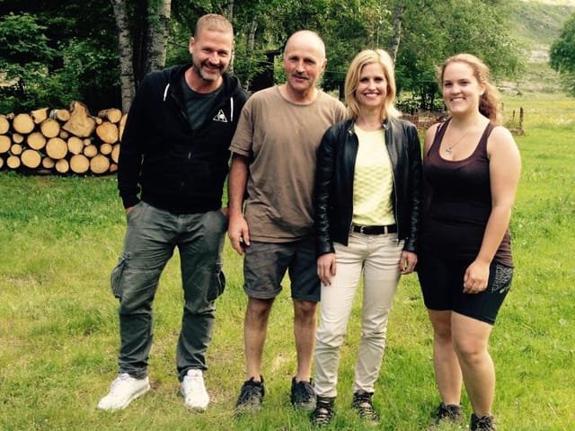 Zwei Männer und zwei Frauen schauen zufrieden in die Kamera, sie stehen auf einer Wiese.