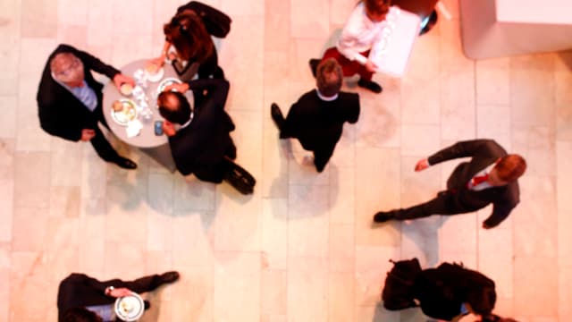 WEF-Teilnehmer von oben in einem Gang gehend und an einem Tischlein stehend. WEF-Teilnehmer von oben in einem Gang gehend und an einem Tischlein stehend.