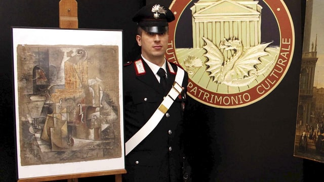 Ein Carabinieri steht neben einem Bild. Ein Carabinieri steht neben einem Bild.